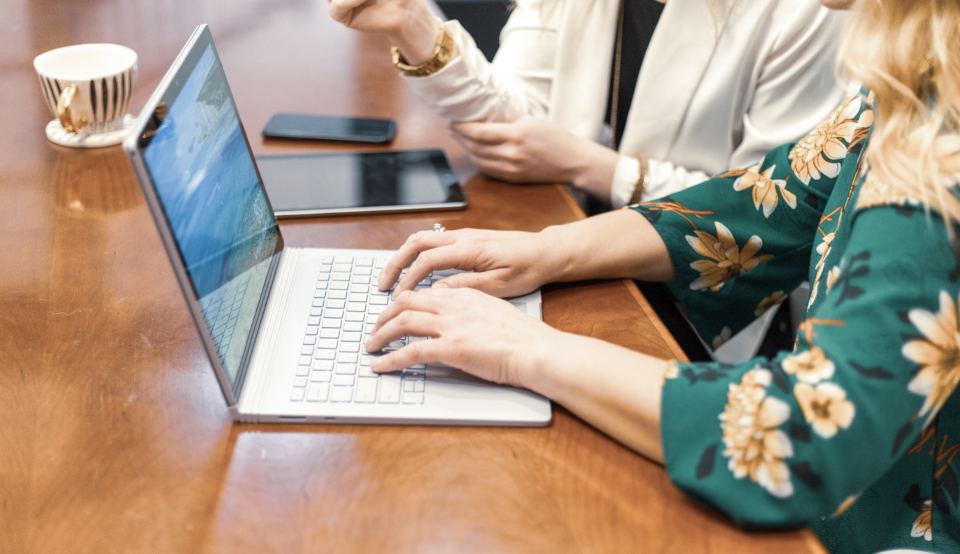 Folk som jobber sammen ved et bord med laptop